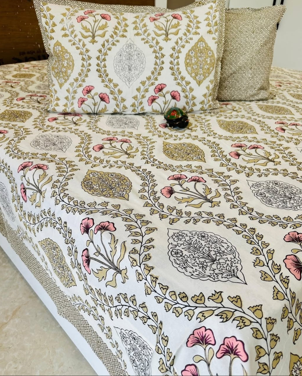 Floral patterned bedspread with matching pillows on a bed.